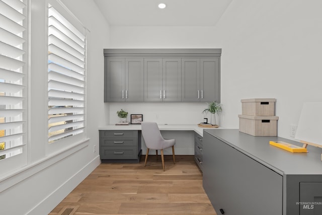 office space with plenty of natural light, light wood-type flooring, and built in desk