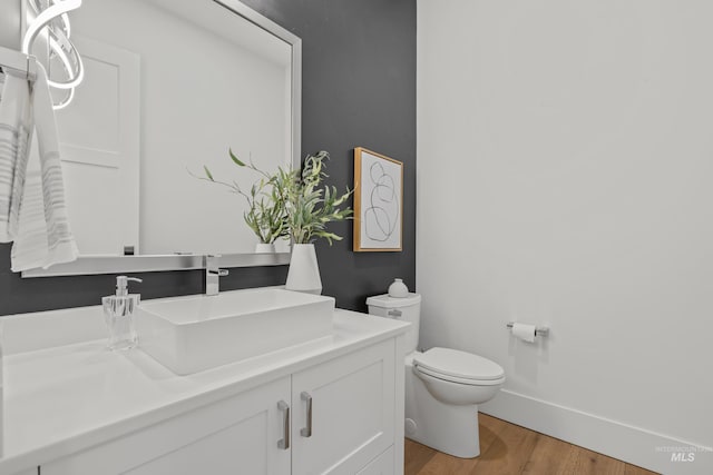 bathroom with wood-type flooring, vanity, and toilet