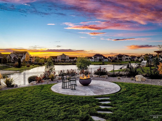 yard at dusk featuring a patio and a water view