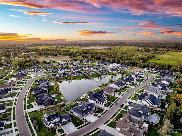 aerial view at dusk featuring a water view