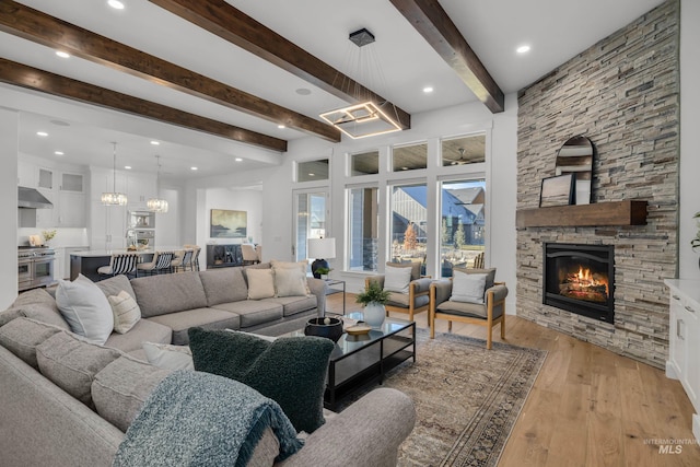 living room with a fireplace, beamed ceiling, and light hardwood / wood-style flooring