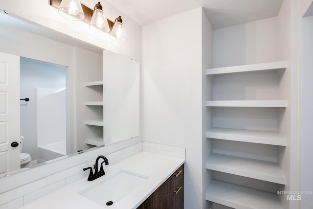 bathroom featuring built in features, vanity, and toilet