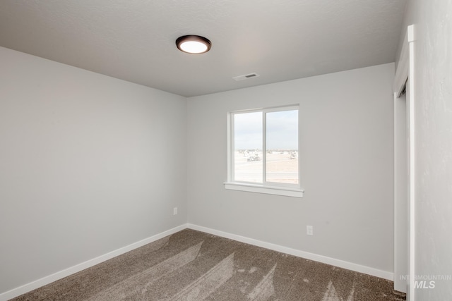 empty room with a textured ceiling and carpet flooring