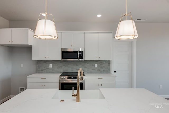 kitchen with decorative backsplash, decorative light fixtures, light stone counters, white cabinetry, and stainless steel appliances