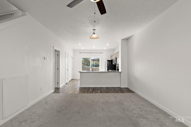 unfurnished living room featuring a textured ceiling, sink, carpet flooring, and ceiling fan