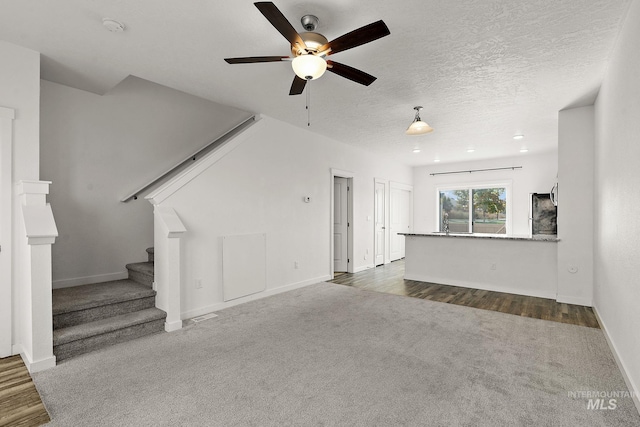 unfurnished living room featuring dark wood-type flooring, a textured ceiling, and ceiling fan