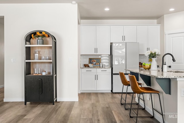 18293 N Begonia Way, Nampa, ID 83687 - kitchen featuring freestanding refrigerator, a sink, light stone countertops, backsplash, and light wood-style flooring