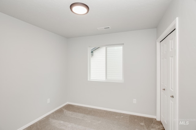 unfurnished bedroom with light carpet, a closet, visible vents, and baseboards