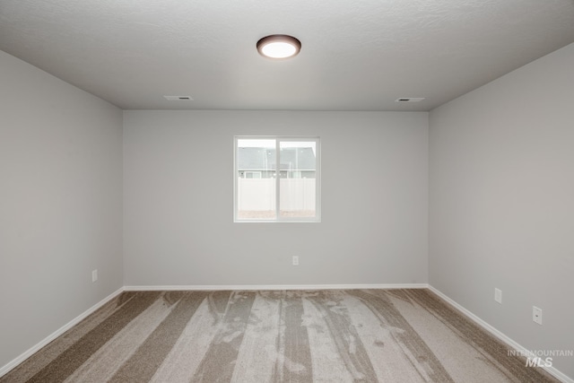 carpeted spare room featuring visible vents and baseboards