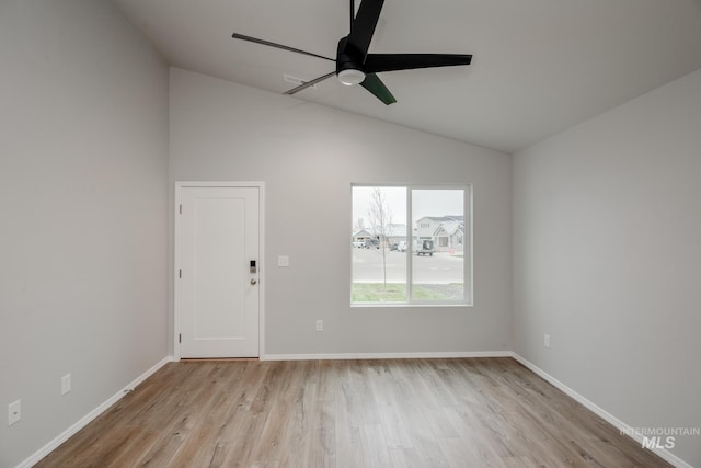 spare room with vaulted ceiling, light wood-style flooring, and baseboards