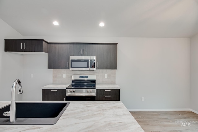 kitchen featuring tasteful backsplash, appliances with stainless steel finishes, light countertops, and a sink