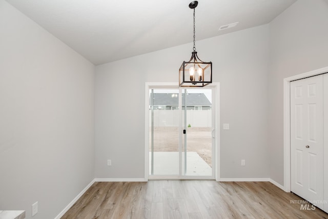 unfurnished dining area with light wood-style floors, lofted ceiling, visible vents, and baseboards