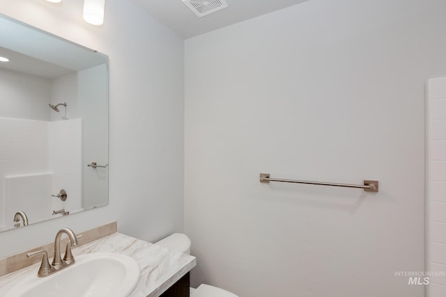 bathroom featuring toilet, visible vents, walk in shower, and vanity