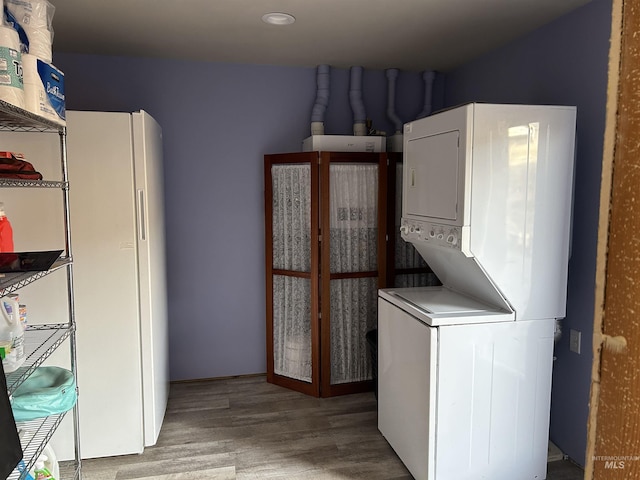 washroom with stacked washer and dryer and light wood-type flooring