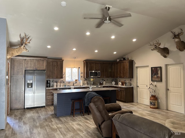 kitchen with hanging light fixtures, a kitchen island with sink, light hardwood / wood-style floors, stainless steel appliances, and dark brown cabinets