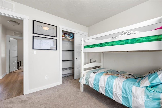 carpeted bedroom featuring baseboards, visible vents, and a closet