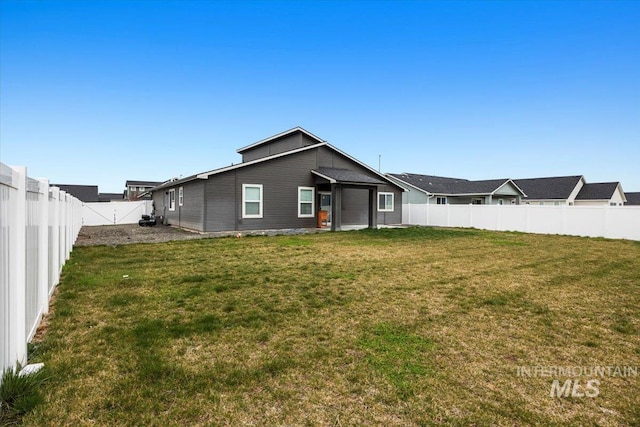 back of house with a lawn and a fenced backyard