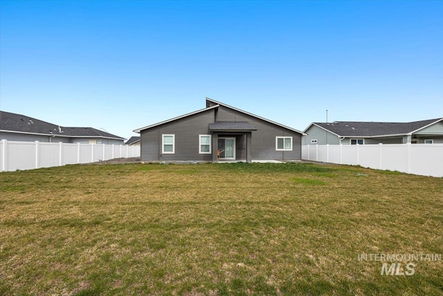 rear view of property featuring fence and a yard