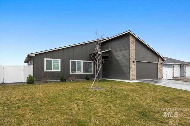 mid-century modern home with fence, a gate, board and batten siding, concrete driveway, and an attached garage