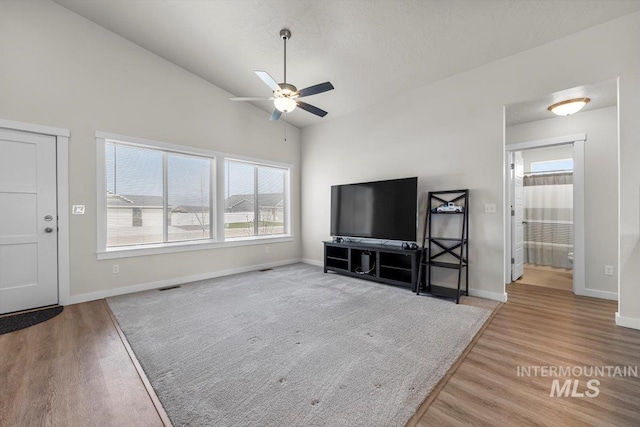 living area featuring baseboards, ceiling fan, wood finished floors, and high vaulted ceiling