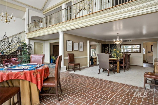 dining room featuring visible vents, ornamental molding, a high ceiling, brick floor, and an inviting chandelier