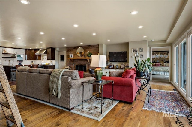 living room featuring a fireplace, recessed lighting, and light wood-type flooring