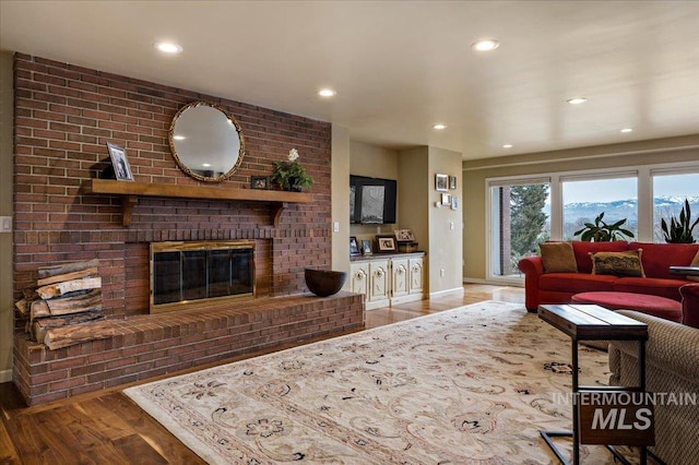 living room featuring a brick fireplace, recessed lighting, wood finished floors, and baseboards