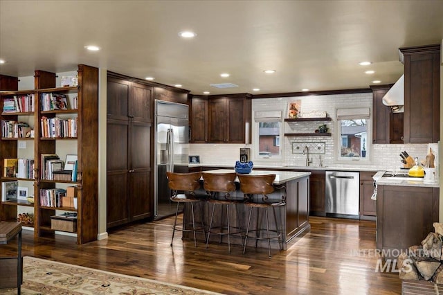 kitchen featuring dark wood-type flooring, dark brown cabinetry, light countertops, appliances with stainless steel finishes, and open shelves