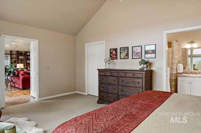 bedroom with high vaulted ceiling, connected bathroom, baseboards, and light carpet