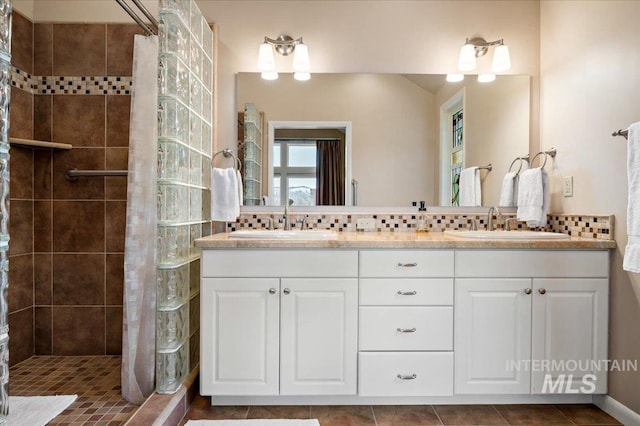 bathroom with tasteful backsplash, a tile shower, and a sink