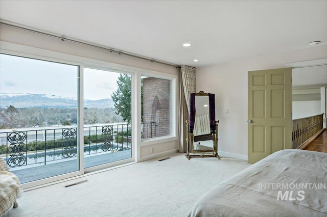 carpeted bedroom with visible vents, baseboards, access to exterior, and a mountain view