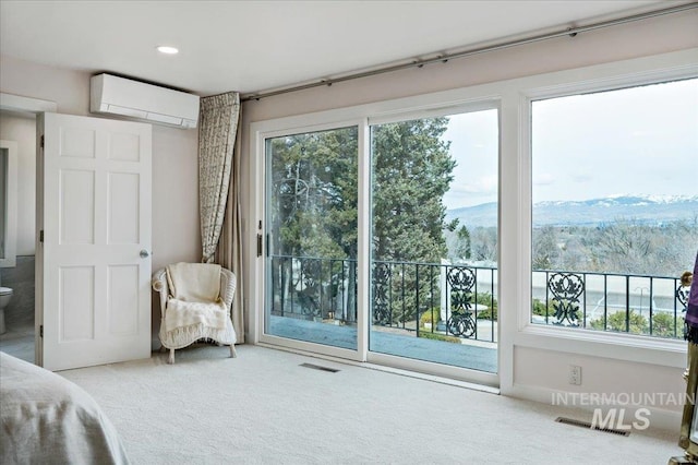 carpeted bedroom with an AC wall unit, access to outside, multiple windows, and a mountain view