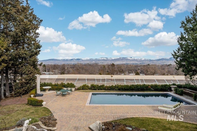 view of swimming pool featuring a patio area, a fenced in pool, and a mountain view