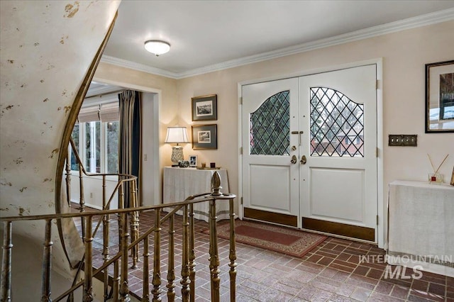 foyer entrance with french doors, brick floor, and ornamental molding