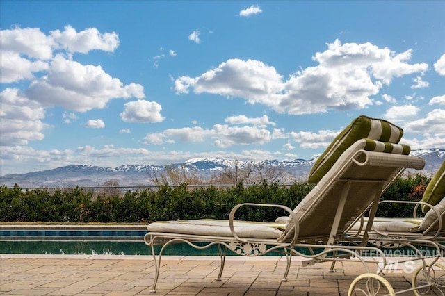 view of swimming pool featuring a patio area, a mountain view, and a covered pool