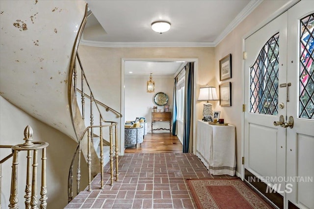 foyer with brick floor, stairway, and crown molding