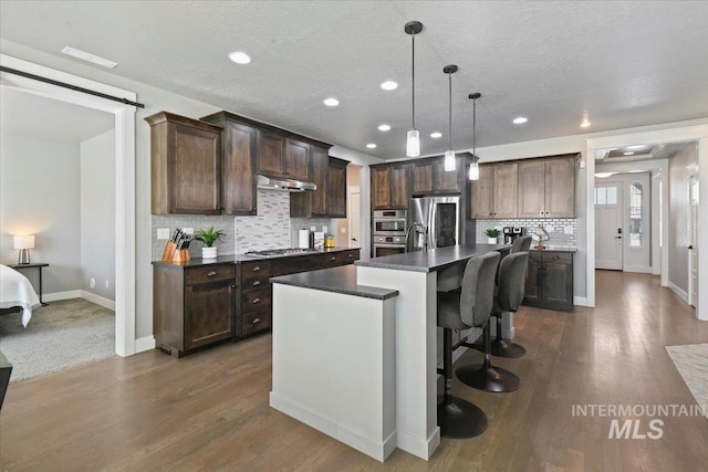 5988 N Lichfield Ave, Meridian, ID 83646 - kitchen featuring under cabinet range hood, stainless steel appliances, dark countertops, and dark brown cabinets