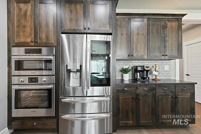 5988 N Lichfield Ave, Meridian, ID 83646 - kitchen featuring dark brown cabinets, appliances with stainless steel finishes, decorative backsplash, and wood finished floors
