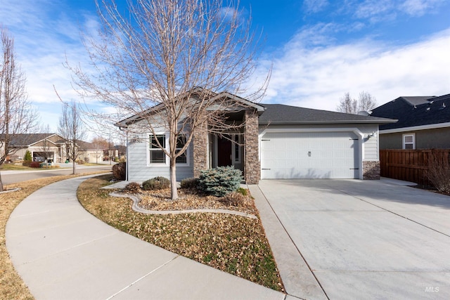 single story home featuring concrete driveway, fence, a garage, and stone siding