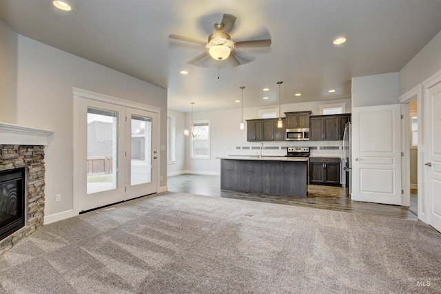 kitchen featuring a sink, open floor plan, dark carpet, dark brown cabinetry, and appliances with stainless steel finishes