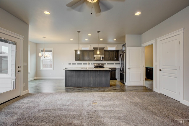 kitchen with stainless steel appliances, light countertops, dark brown cabinets, ceiling fan with notable chandelier, and dark carpet