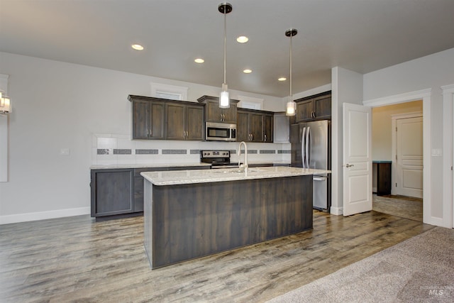 kitchen featuring decorative backsplash, dark brown cabinetry, wood finished floors, and appliances with stainless steel finishes