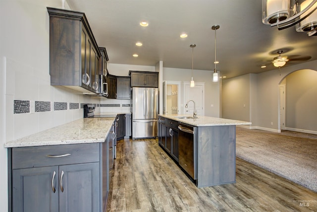 kitchen with a sink, tasteful backsplash, arched walkways, appliances with stainless steel finishes, and dark brown cabinets