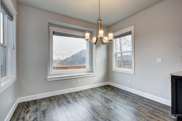 unfurnished dining area with a notable chandelier, visible vents, baseboards, and dark wood-style flooring