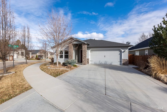 view of front of property with stone siding, an attached garage, driveway, and fence