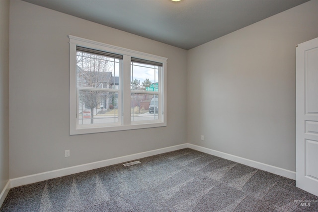 empty room featuring carpet flooring, baseboards, and visible vents