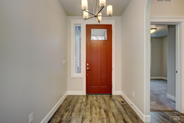 foyer entrance with visible vents, baseboards, an inviting chandelier, and dark wood-style flooring