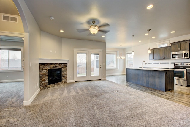 kitchen featuring visible vents, ceiling fan with notable chandelier, dark brown cabinetry, appliances with stainless steel finishes, and light colored carpet