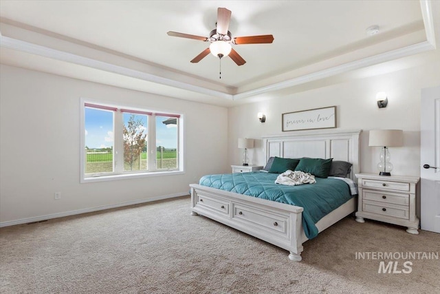 carpeted bedroom with ceiling fan and a tray ceiling