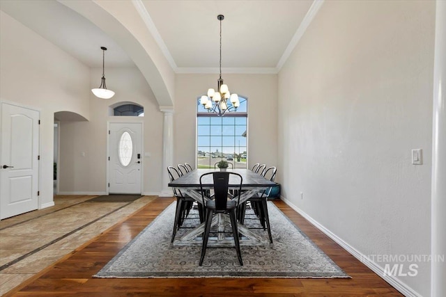 dining space with crown molding, a high ceiling, a chandelier, and dark hardwood / wood-style floors